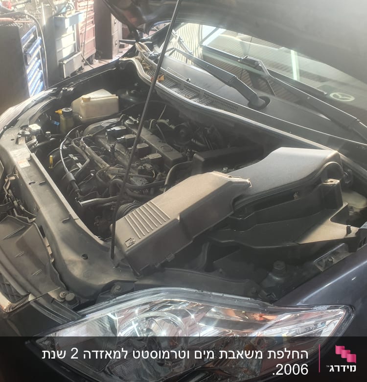 מנוע רכב פתוח עם מכסה מנוע מורם במוסך